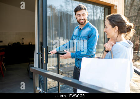 Young couple entering home carrying shopping bags. Happy purchase and modern living concept Stock Photo