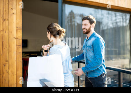 Young couple entering home carrying shopping bags. Happy purchase and modern living concept Stock Photo