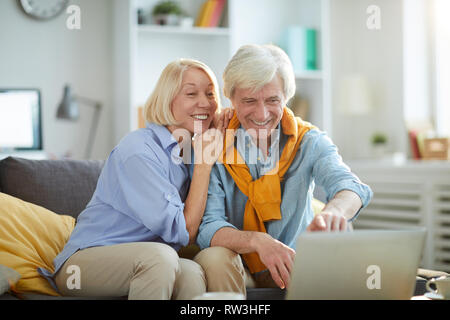 Portrait of happy mature couple using laptop while enjoying weekend at home , copy space Stock Photo