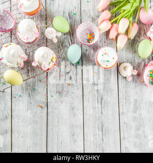 Easter kids party treat. Festive Easter food. Homemade cupcakes with cream and marshmallow cute bunny rabbits with paws. On a white wooden table, top  Stock Photo