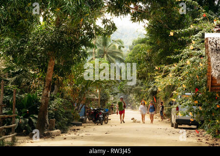 Port Barton, Palawan, Philippines - February 3, 2019: People walk along street with dirt road in traditional Philippine village Stock Photo