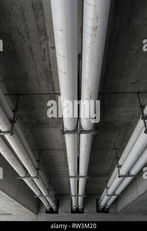 white industrial sewage and water pipes underneath a concrete bridge in Switzerland Stock Photo