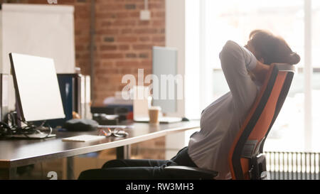 Calm businesswoman worker holding hands behind head relaxing in chair Stock Photo