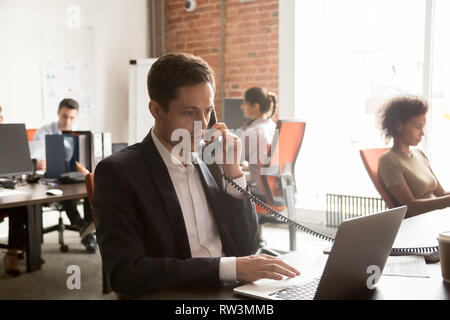 Serious businessman making call negotiating consulting customer looking at laptop Stock Photo