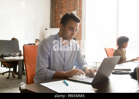 Focused mature businessman working with laptop documents in modern office Stock Photo
