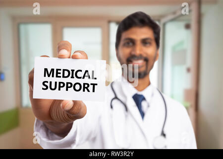 Friendly indian doctor man presenting medical support black text on white business card Stock Photo