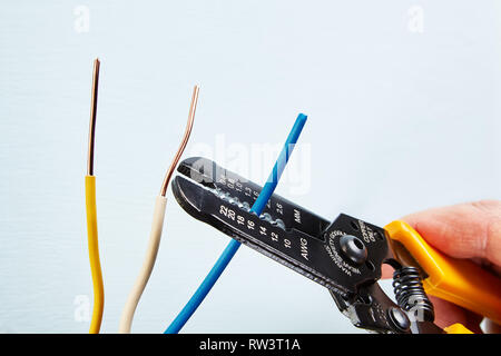 Electrician uses wire stripper tool during electrical wiring services. Stock Photo