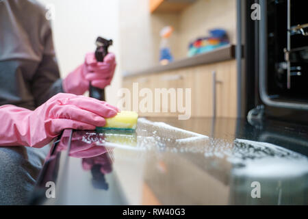 Image of woman's hands in rubber gloves washing oven