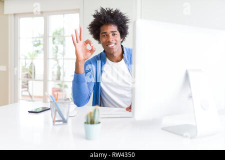 African American man working using computer doing ok sign with fingers, excellent symbol Stock Photo