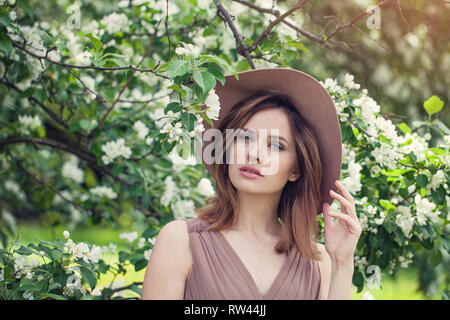 Outdoor fashion photo of beautiful young woman in flowers. Spring blossom Stock Photo