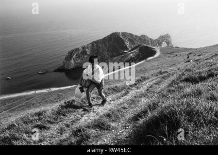 Lulworth Cove photographed in 1985. Lulworth Cove is a cove near the village of West Lulworth, on the Jurassic Coast in Dorset, southern England. The cove is one of the world's finest examples of such a landform, and is a World Heritage Site and tourist location with approximately 500,000 visitors every year, of whom about 30 percent visit in July and August.[1] It is close to the rock arch of Durdle Door and other Jurassic Coast sites. Stock Photo