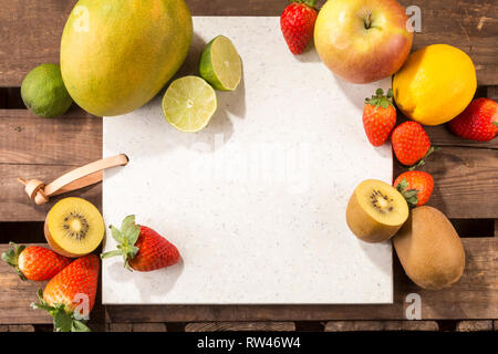 Concrete stone server with space for text on a rustic wood plank surface. and arranged fruits. Apple, lemon, strawberries, kiwis, limes and mango. Stock Photo
