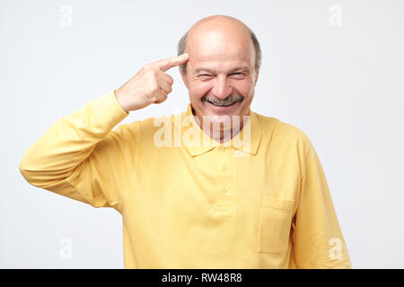 Handsome middle age hoary senior man smiling pointing to head with one finger, great idea or thought, good memory Stock Photo