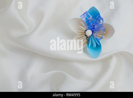 Beautiful colourful folded origami flower on a white shiny textile background Stock Photo