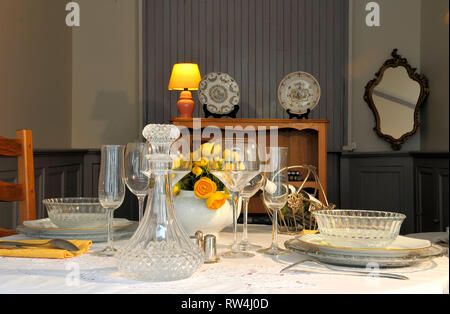 Rich set table on old fashioned dining room table with wine and flowers Stock Photo