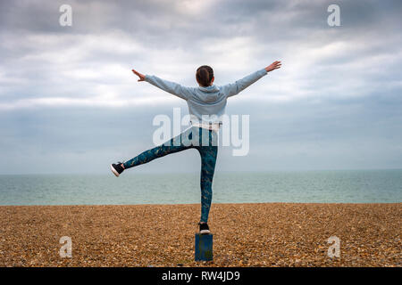 Woman standing with arms raised on beach, back view, copyspace Stock Photo