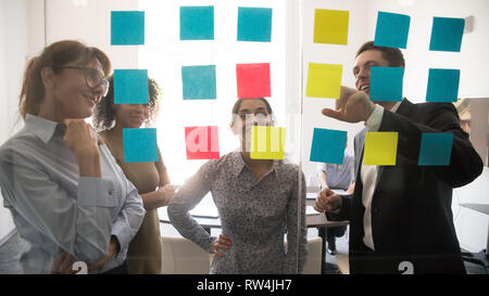 Diverse team people looking at sticky notes on glass brainstorming Stock Photo