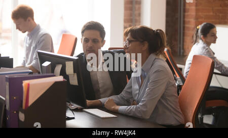Serious colleagues working together in modern office talking using computer Stock Photo