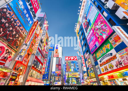 TOKYO, JAPAN - AUGUST 1, 2015: Crowds pass below colorful signs in Akihabara. The historic district electronics has evolved into the shopping area for Stock Photo