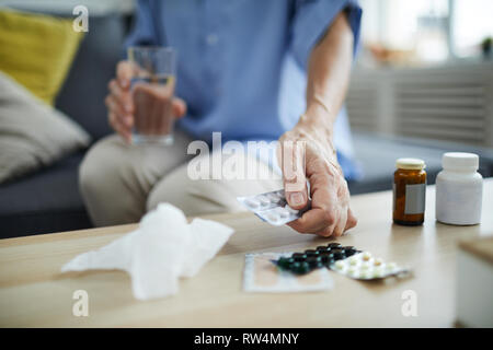 Closeup of unrecognizable senior woman taking pills and medication off table at home, copy space Stock Photo