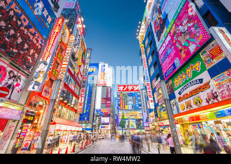 TOKYO, JAPAN - AUGUST 1, 2015: Crowds pass below colorful signs in Akihabara. The historic district electronics has evolved into the shopping area for Stock Photo