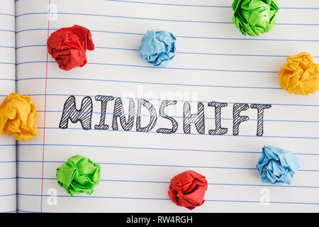 Mindshift. Word Mindshift on notebook sheet with some colorful crumpled paper balls around it. Close up. Stock Photo