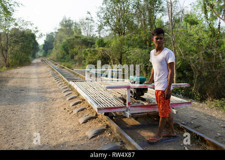 Men placing the bamboo platform on the wheels, the bamboo train; Battambang, Cambodia Stock Photo