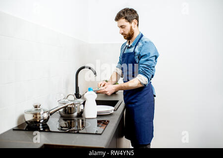 Man washing dishes at home stock photo. Image of handsome - 141020840