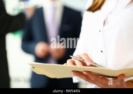 Female arm in shirt hold silver pen and pad making Stock Photo