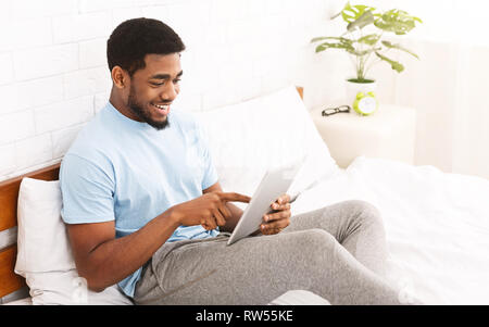 Relaxed casual man using smartphone in bed Stock Photo