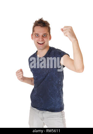 A young very happy man standing in a blue sweater and gray jeans,  smiling, with his fists up into the air, isolated for white background Stock Photo