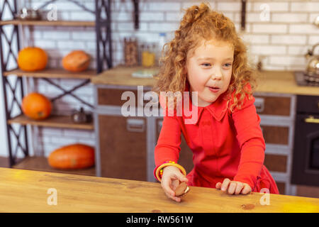 Charming blonde curly-haired girl leaning on table Stock Photo