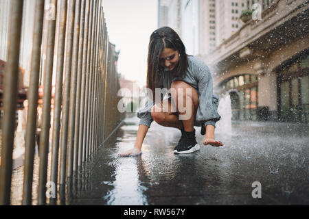 girl playing and dancing around on a wet street Stock Photo