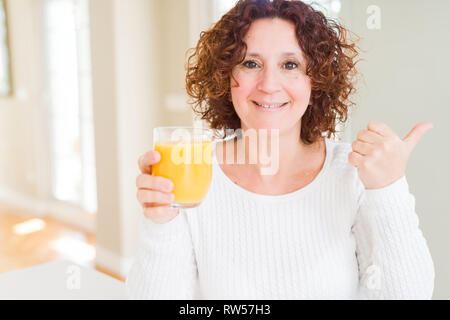 Senior woman driking a fresh glass of water pointing and showing with ...