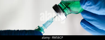 Physician injector arms in sterile uniform holding syringe Stock Photo