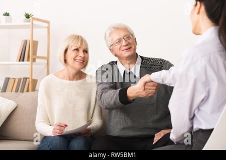 Happy senior couple sealing contract with financial advisor Stock Photo