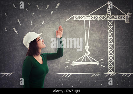 Side view of angry woman engineer raising hand up and scolding someone. Negative human emotion over blackboard with crane construction crane sketch. F Stock Photo