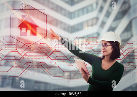 Woman construction engineer, wearing protective helmet, using tablet computer gadget, display digital house, measuring dimensions and make calculation Stock Photo