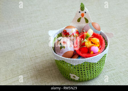 Wicker basket of green color with Easter set of decorated eggs. Stock Photo