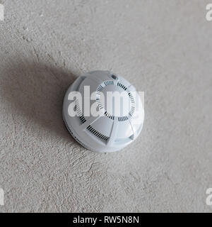 Smoke detector fire alarm on the grey wall. Copyspace for text. Stock Photo