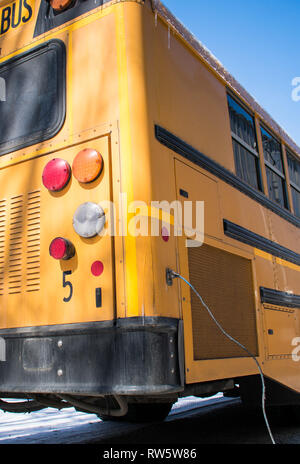 Low angle view of a US school bus in winter with block heater plugged in Stock Photo