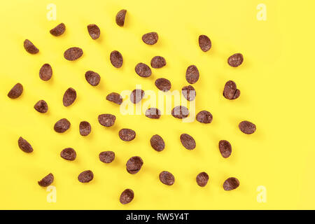 Top down view, chocolate cornflakes scattered on yellow board. Stock Photo