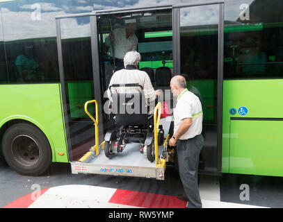 A bus driver assists a disabled woman in a wheelchair to board his bus using a platform lift,  Santa Cruz de Tenerife, Tenerife Stock Photo