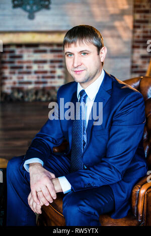 Portrait of a handsome man in a business suit in a loft interior. Businessman standing with arms crossed. Stock Photo