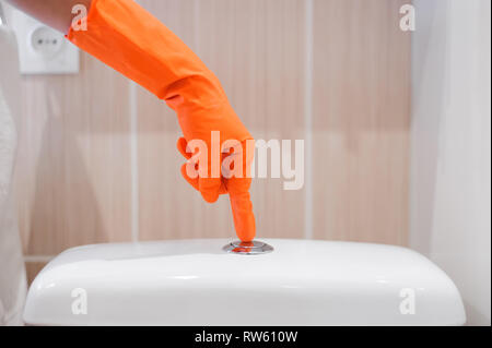 woman's finger pushing button and flushing toilet Stock Photo