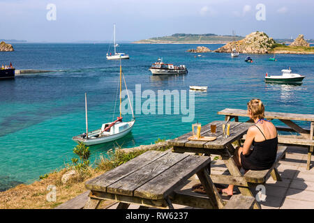 Sitting on the terrace of the Turk's Head, looking out over Porth Conger and the island of Gugh, St. Agnes, Isles of Scilly, UK Stock Photo