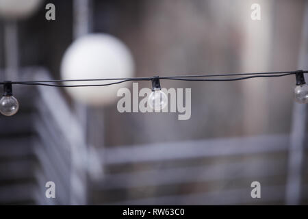 Turned off light bulbs in a row on a cable Stock Photo
