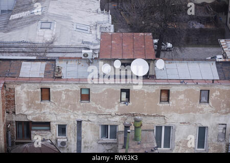 Inhabited, old and decayed (almost ruined) building in the old part of Bucharest, Romania, with worn out satellite antennas on the rusty metal roof Stock Photo