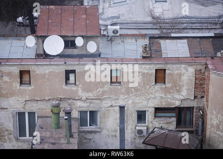 Inhabited, old and decayed (almost ruined) building in the old part of Bucharest, Romania, with worn out satellite antennas on the rusty metal roof Stock Photo
