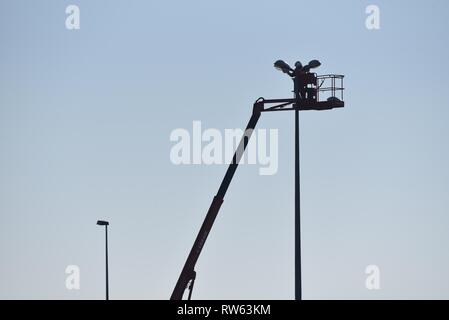 Street light maintenance — an electrical engineer carries out his work on street lighing at height using a cherry picker Stock Photo
